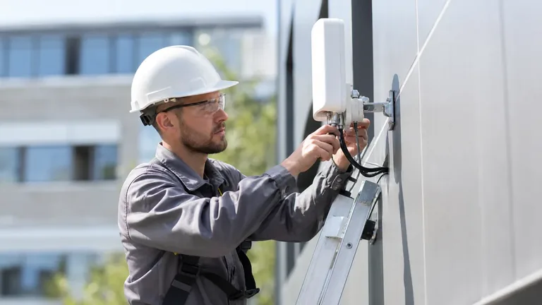 Tecnico durante l'installazione FWA Tecnico delle telecomunicazioni durante l'installazione di un'antenna FWA su un edificio